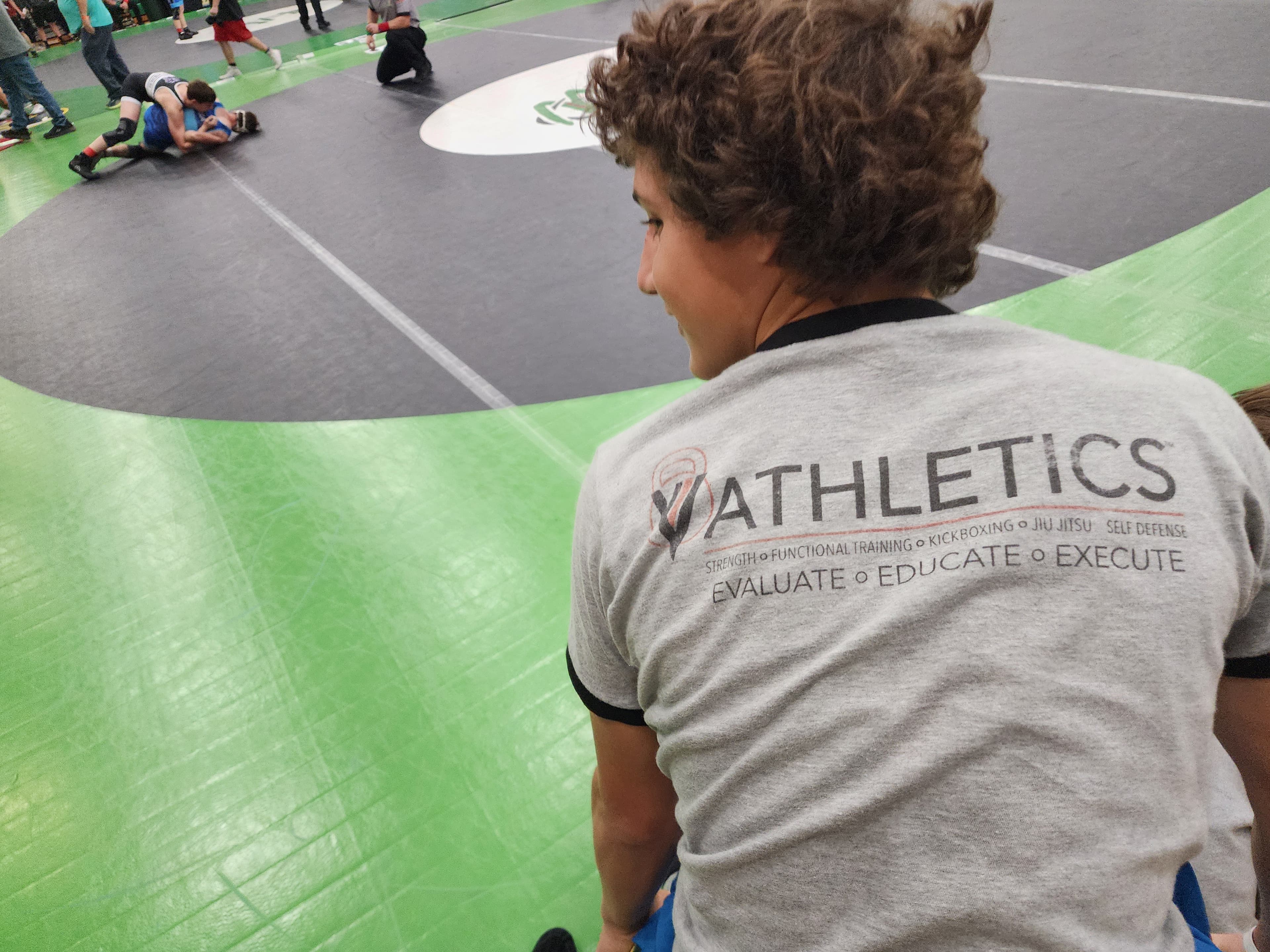 Athlete wearing a VVV Athletics shirt at a wrestling meet